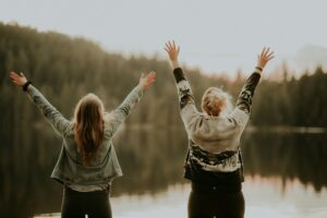 two-women-hands-up-lake-priscilla-du-preez-zeqWK0n5PNM-unsplash(https-::unsplash.com:photos:two-women-hands-up-standing-beside-body-of-water-zeqWK0n5PNM)