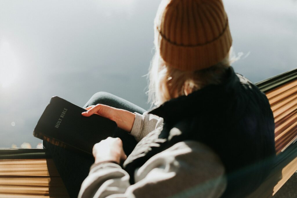 A woman seated holding a bible while looking into the distance symbolizing fellowship with God