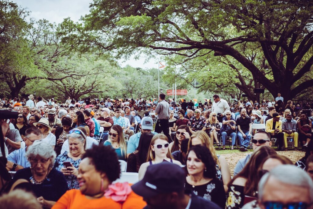 A mixed crowd of people seated in a park with trees symbolizing how all kinds of people could have life forever through Jesus' death and resurrection