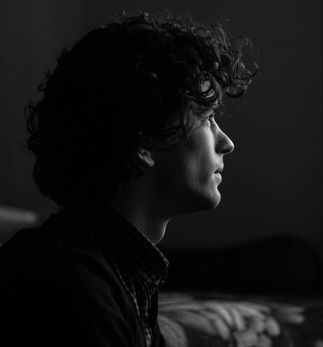 A black and white headshot photograph of a man seated looking forward with a facial expression of someone with distant thoughts.